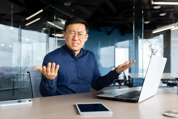 Porträt eines frustrierten und wütenden Chefs im Büro asiatischer Mann, der in die Kamera schaut und verärgert schreit