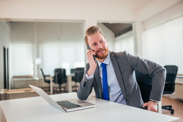 Porträt eines Geschäftsführers, der am Telefon bei der Arbeit spricht.