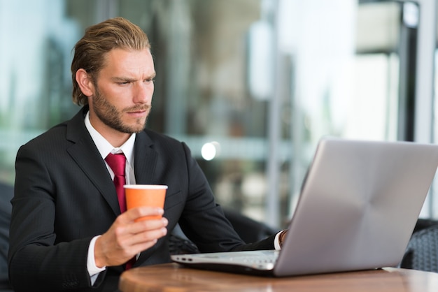 Porträt eines Geschäftsmannes, der seine Laptop-Computer in einer Kaffeestube verwendet