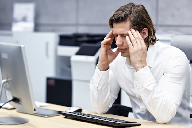 Porträt eines Geschäftsmannes mit Kopfschmerzen am Arbeitsplatz hautnah