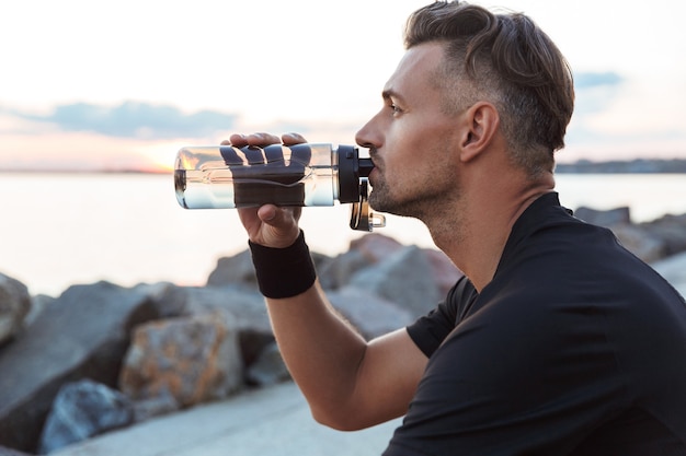 Porträt eines gesunden Sportlers, der Wasser aus einer Flasche trinkt