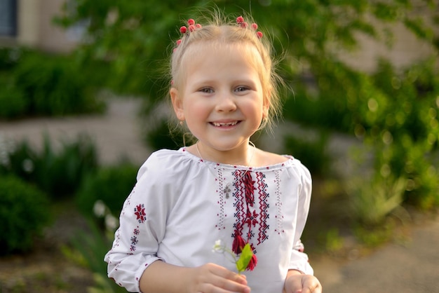 Porträt eines glücklich lächelnden Vorschulmädchens mit einer Blume in einem ukrainischen bestickten Hemd