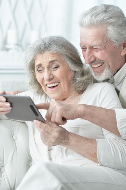 Foto porträt eines glücklichen älteren paares, das zu hause ein tablet benutzt