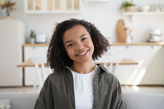 Porträt eines glücklichen Afro-Mädchens zu Hause Lockige Frisur, optimistisches Lächeln und positive Emotionen