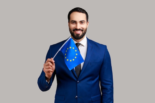 Porträt eines glücklichen bärtigen Mannes, der die EU-Flagge zeigt und in die Kamera-Einwanderung lächelt