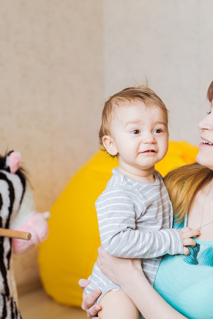 Porträt eines glücklichen entzückenden Babys mit Mutter drinnen