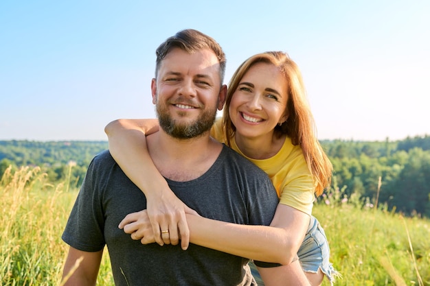 Porträt eines glücklichen erwachsenen umarmenden Paares an einem sonnigen Sommertag