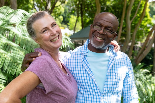 Porträt eines glücklichen, gemischtrassigen älteren Paares, das mit den Armen um die Schultern im Hinterhof steht