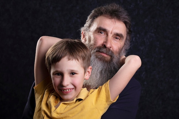 Porträt eines glücklichen Großvaters mit Bart und Enkel auf schwarzem Hintergrund