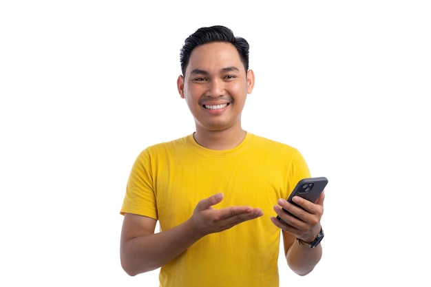 Porträt eines glücklichen, hübschen asiatischen Mannes, der ein Smartphone für den Handel oder das Gespräch benutzt, der in die Kamera schaut und lächelt, isoliert auf weißem Hintergrund