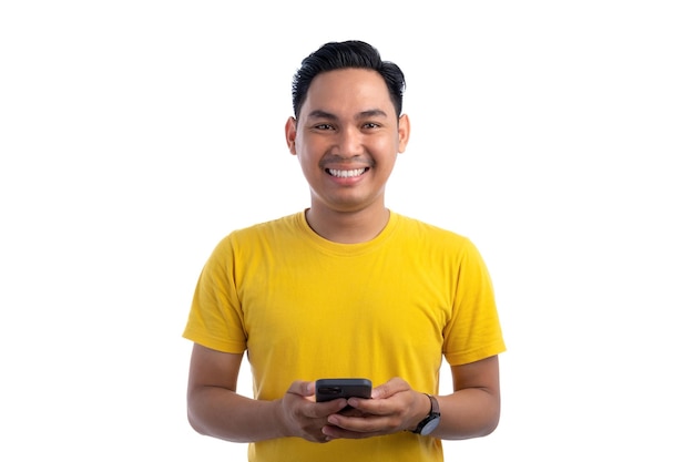 Porträt eines glücklichen, hübschen asiatischen Mannes, der ein Smartphone für den Handel oder das Gespräch benutzt, der in die Kamera schaut und lächelt, isoliert auf weißem Hintergrund