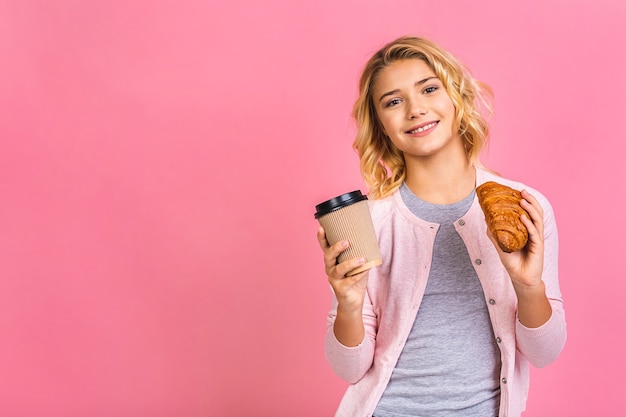 Porträt eines glücklichen hübschen jugendlich Kindermädchens, das Croissant isst und einen Kaffee trinkt