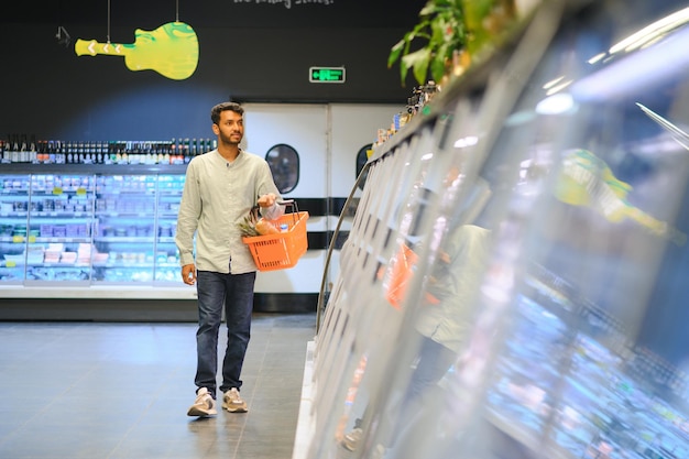 Porträt eines glücklichen, hübschen jungen Indiens im Lebensmittelgeschäft oder Supermarkt