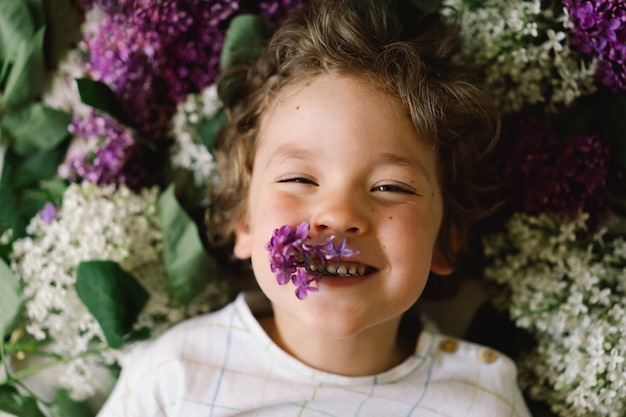 Porträt eines glücklichen Jungen in lila Blumen. Glückliche Kindheit. Frühlingszeit