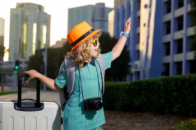 Porträt eines glücklichen Kinderreisenden mit Gepäck Positiver kleiner Tourist mit Koffer bereit zum Reisen Glücklicher Kindertourist mit Gepäck, das in den Urlaub reisen wird