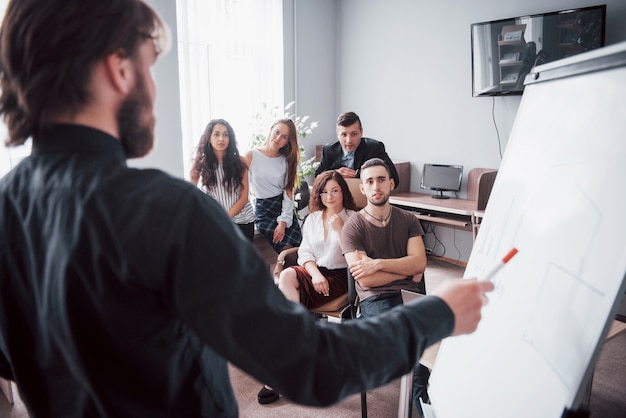 Porträt eines glücklichen kreativen Teams von Leuten, die während des Treffens im Büro sprechen.