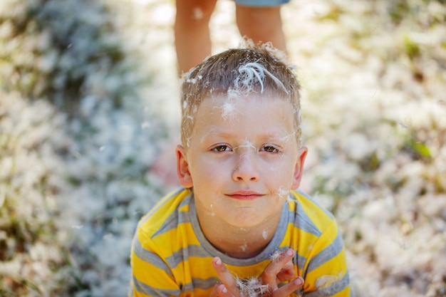 Porträt eines glücklichen lächelnden Jungen mit Federn von den Kissen