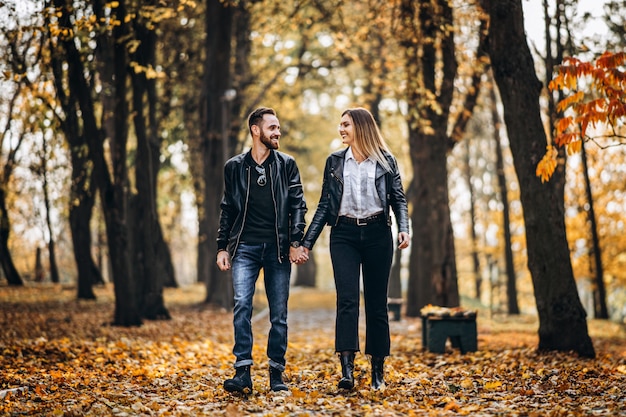 Porträt eines glücklichen liebenden Paares, das draußen im Herbstpark geht