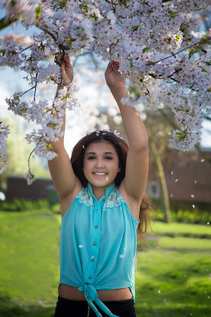 Porträt eines glücklichen Mädchens, das bei einem Blumenbaum steht