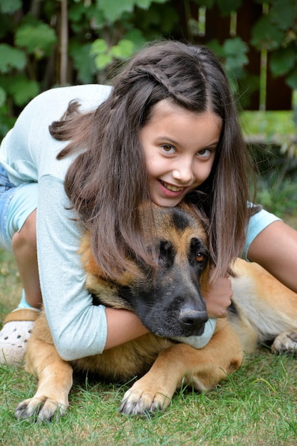 Porträt eines glücklichen Mädchens, das einen Hund auf dem Gras umarmt