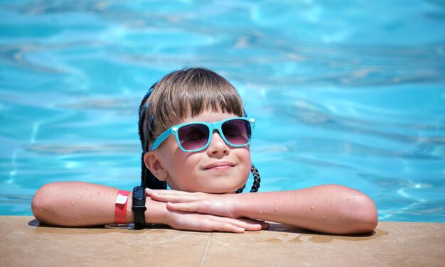 Porträt eines glücklichen Mädchens, das sich an sonnigen Sommertagen während der tropischen Ferien am Swimmingpool entspannt