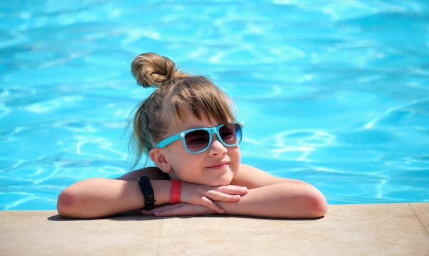 Porträt eines glücklichen Mädchens, das sich an sonnigen Sommertagen während der tropischen Ferien am Swimmingpool entspannt