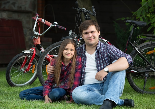 Porträt eines glücklichen Mannes und eines jungen Mädchens, die sich nach dem Fahrradfahren im Park entspannen?