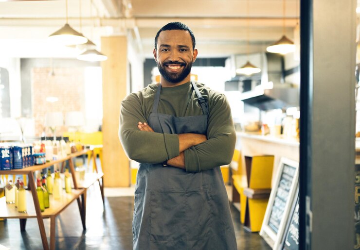 Foto porträt eines glücklichen mannes und kleinunternehmers eines cafés mit gekreuzten armen im vertrauen oder im einzelhandelsmanagement mann barista oder kellner lächeln am eingang des cafés oder bereit für den service