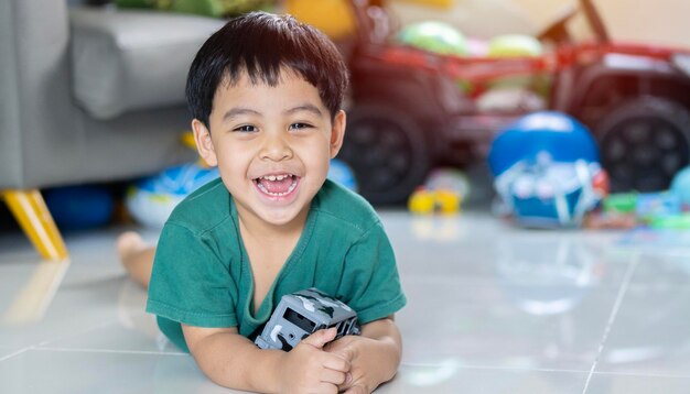 Porträt eines glücklichen schwarzhaarigen Kindes, das fröhlich lacht und im Wohnzimmer ein Autospielzeug umarmt