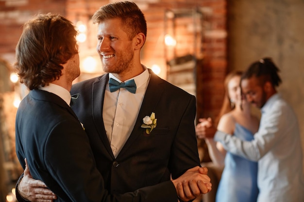 Porträt eines glücklichen schwulen Paares, das während der Hochzeitszeremonie zusammen tanzt