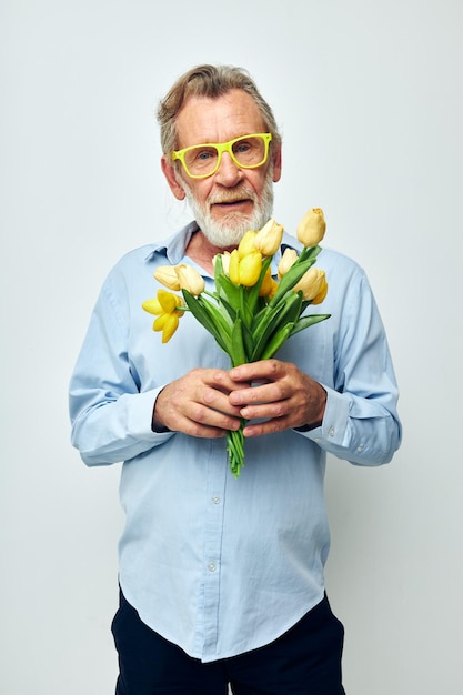 Porträt eines glücklichen Senioren ein Blumenstrauß mit Brille als Geschenk heller Hintergrund