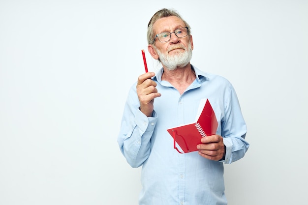 Porträt eines glücklichen Senioren mit rotem Notizbuch und hellem Hintergrund