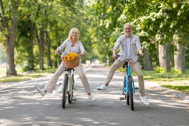 Porträt eines glücklichen Seniorenpaares, das im Sommerpark Fahrräder fährt