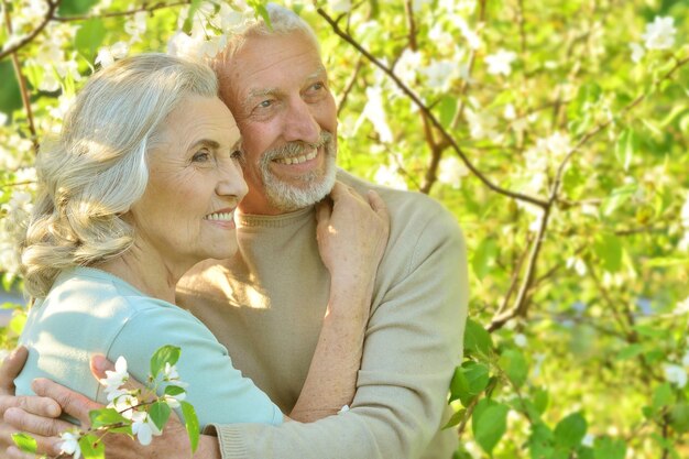 Porträt eines glücklichen Seniorenpaares, das unter einem blühenden Baum steht