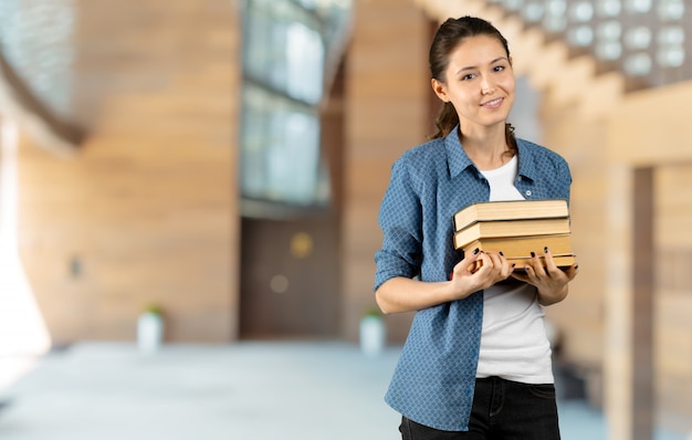 Porträt eines glücklichen Studentenmädchens oder -frau mit Büchern in der Bibliothek