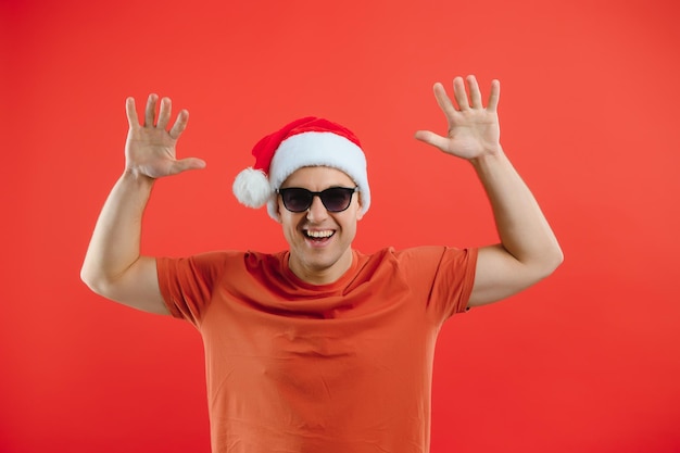 Porträt eines glücklichen und aufgeregten Mannes mit Weihnachtsmütze, der sich freut und etwas gewinnt, das das neue Jahr feiert, das über rotem Hintergrund steht