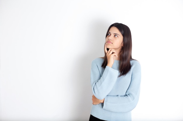 Porträt eines grüblerischen Teenager-Mädchens mit dunklen Haaren in einer blauen Bluse Weißer Hintergrund Platz für Text