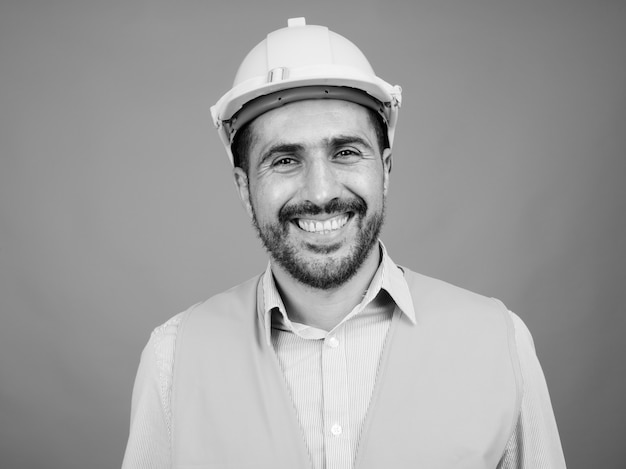 Porträt eines gutaussehenden bärtigen persischen Bauarbeiters auf Grau in Schwarz und Weiß