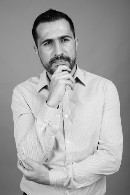 Porträt eines gutaussehenden bärtigen persischen Geschäftsmannes auf Grau in Schwarzweiß