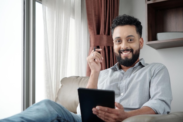 Porträt eines gutaussehenden glücklichen bärtigen Mannes, der auf Tablet-Computer lächelt und Skizze zeichnet