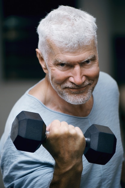 Porträt eines gutaussehenden grauhaarigen älteren Mannes mit einem Hantel-Sport- und Gesundheitskonzept