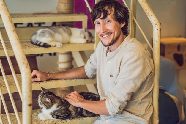 Porträt eines gutaussehenden jungen Mannes, der mit Katze spielt und Kaffee trinkt