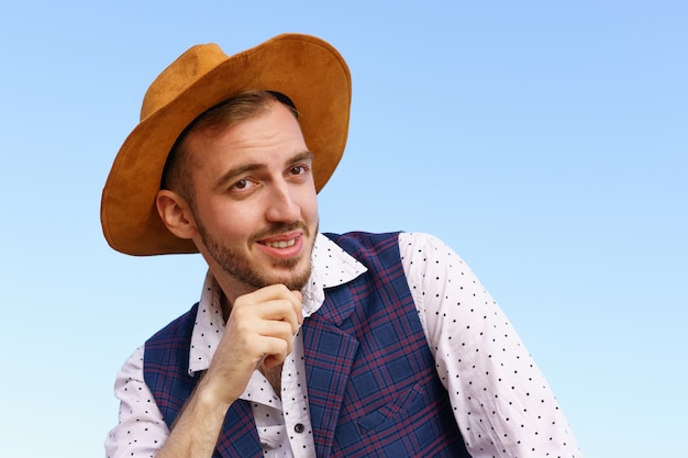 Porträt eines gutaussehenden jungen Mannes mit Hut vor einem kaukasischen Kerl mit blauem Himmel mit einem Spitzbart, der glücklich...