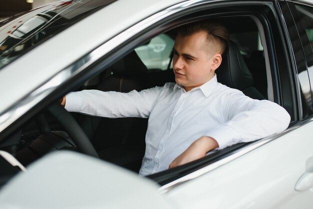 Porträt eines gutaussehenden lächelnden Geschäftsmannes, der sein Auto fährt