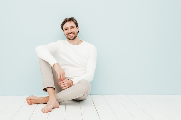 Porträt eines gutaussehenden lächelnden Hipster-Lumbersexual-Geschäftsmann-Modells, das einen lässigen weißen Pullover und eine Hose trägt