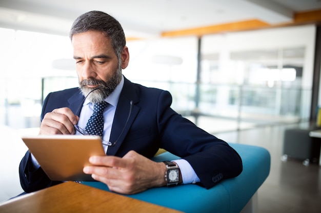 Porträt eines gutaussehenden leitenden Geschäftsmannes mit digitalem Tablet im modernen Büro