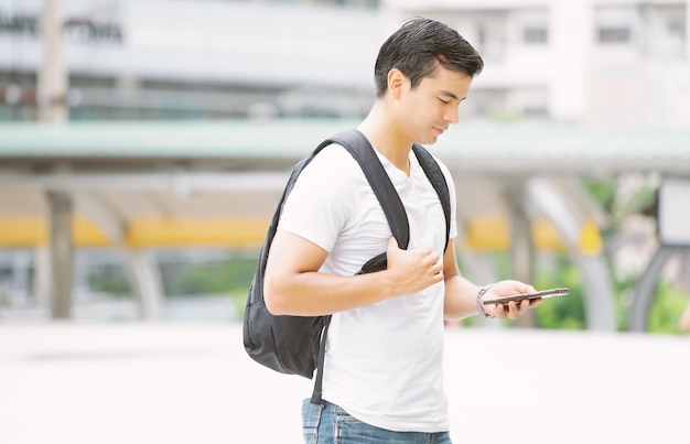 Porträt eines gutaussehenden Mannes, der die Straße hinuntergeht und in der Stadt eine SMS auf dem Smartphone schreibt Neues normales Technologiekonzept