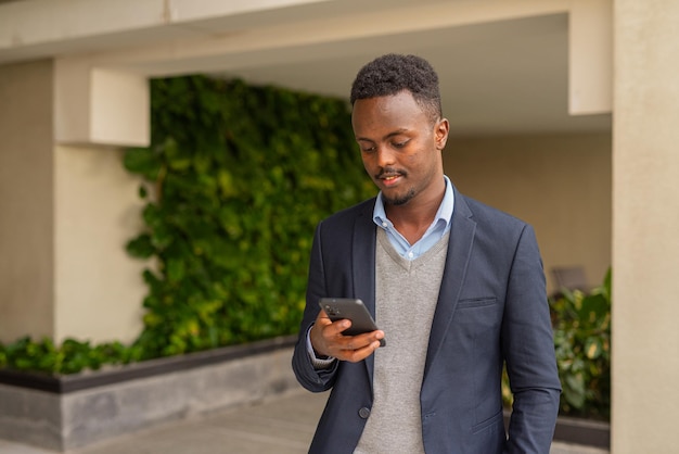 Porträt eines gutaussehenden schwarzen afrikanischen Geschäftsmanns, der mit dem Handy SMS schreibt