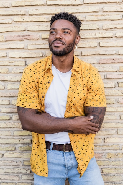 Porträt eines gutaussehenden schwarzen Mannes, der mit einem Ziegelsteinhintergrund lächelt