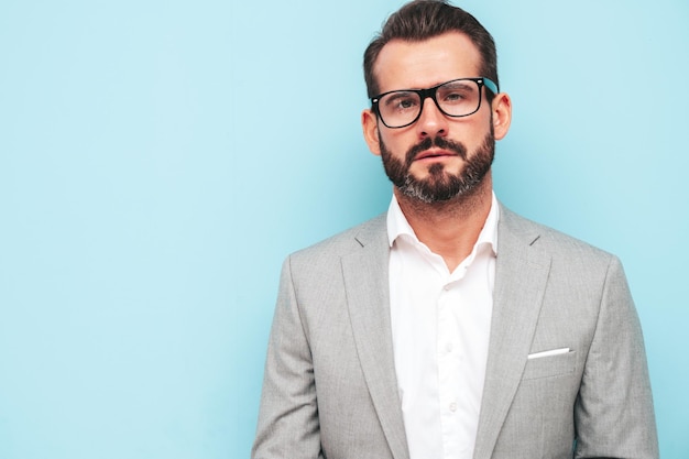 Porträt eines gutaussehenden, selbstbewussten, stilvollen Hipster-Lambersexuellen ModelsSexy moderner Mann in elegantem Anzug und Brille Mode männlich posiert im Studio in der Nähe der blauen Wand Blick in die Kamera mit Brille